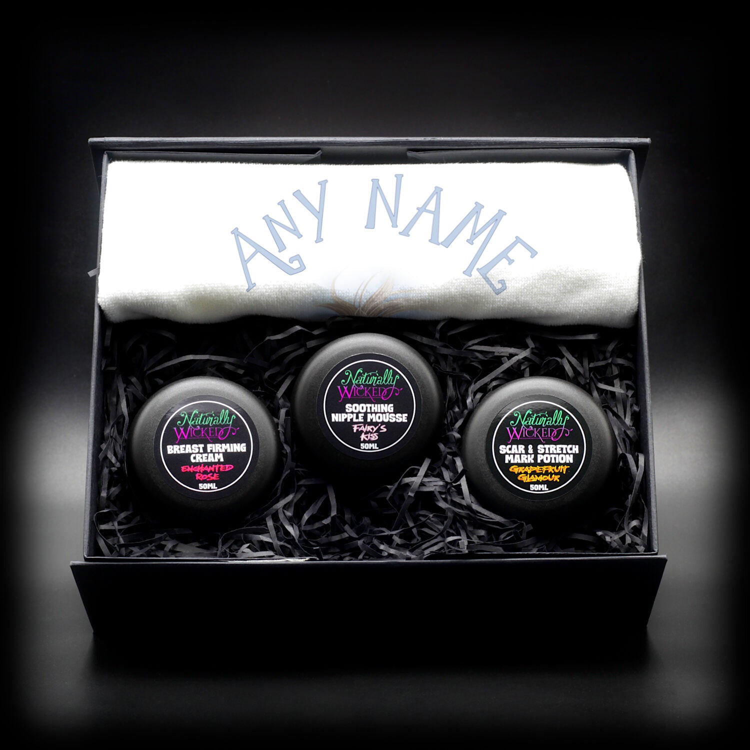 Naturally Wicked Personalized Gift Set with Breast Firming Cream, Nipple Mousse, and Scar & Stretch Mark Potion, customized with ‘Any Name’ on a soft white towel.