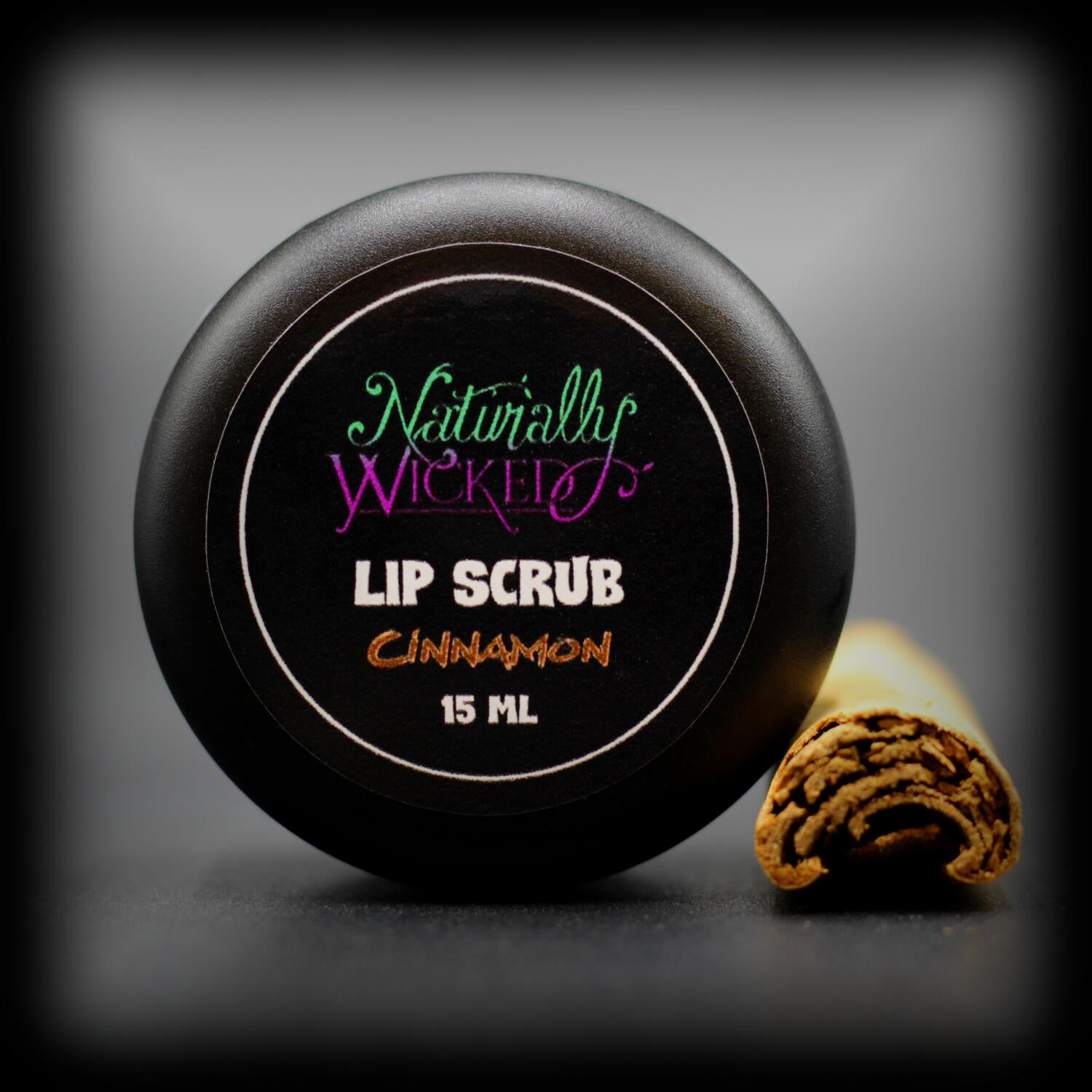 Naturally Wicked Cinnamon Lip Scrub Luxury Labelled Lid Beside Brown Spicy Cinnamon Stick