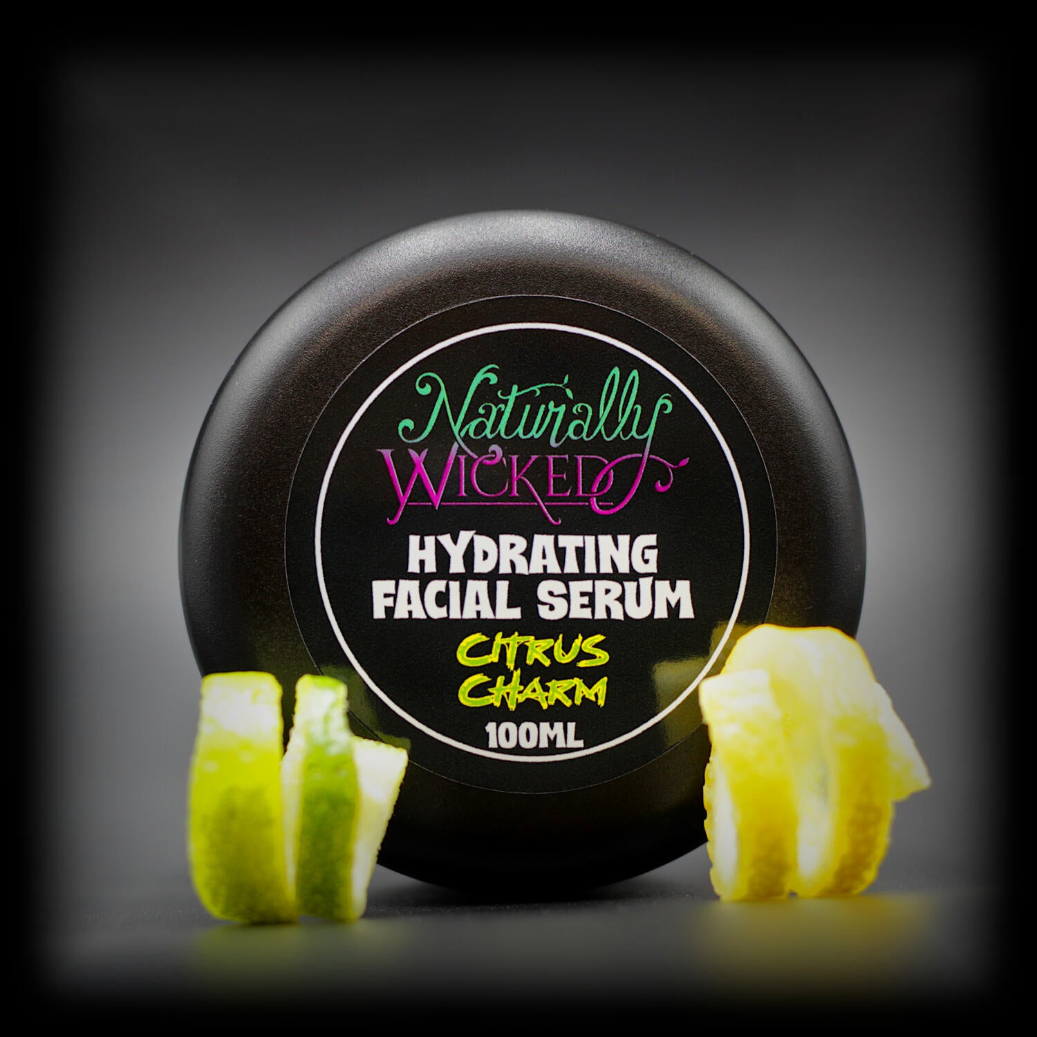 Naturally Wicked Citrus Charm Hydrating Facial Serum in sleek black jar, styled with lemon and lime twists.