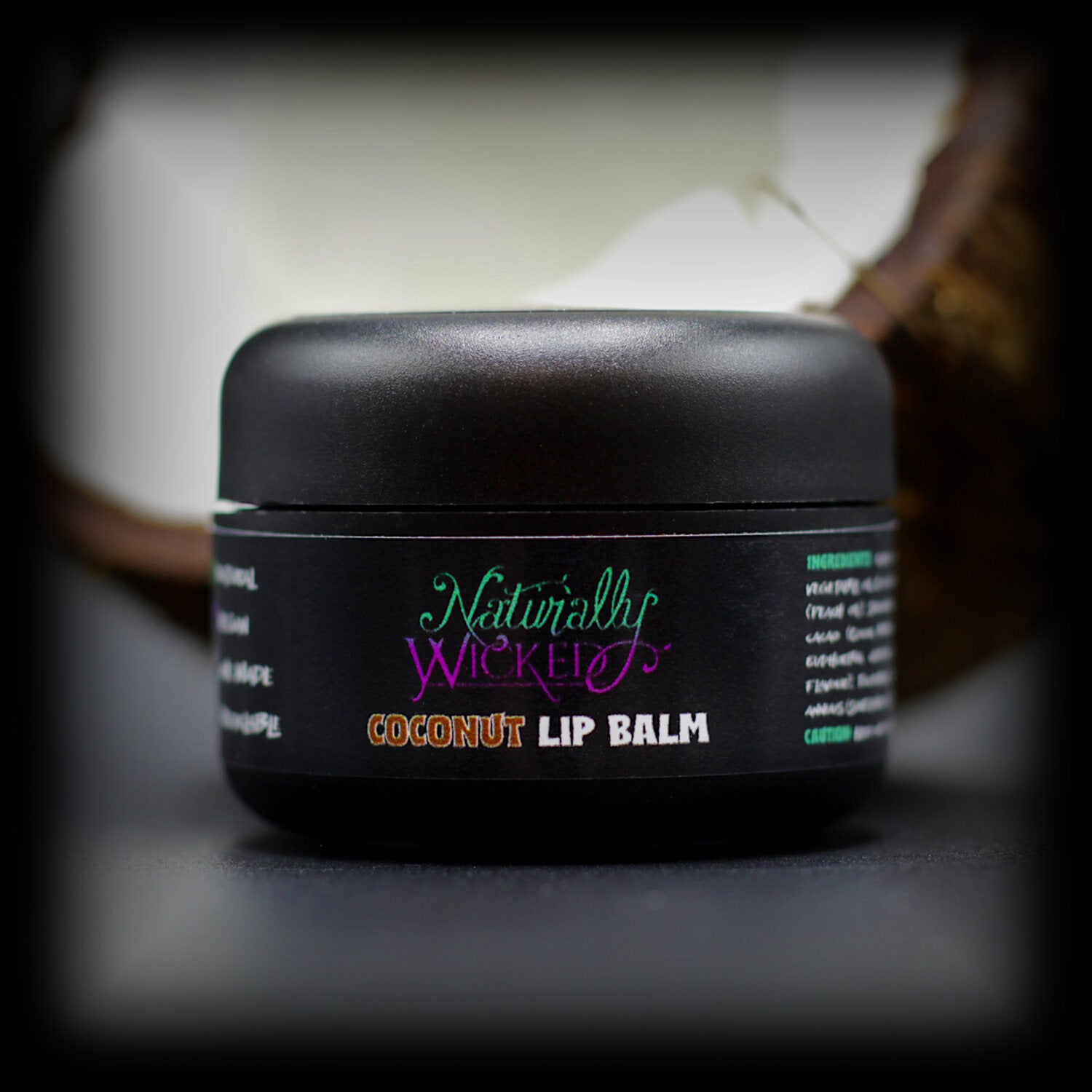 Naturally Wicked Coconut Lip Balm Beside Cracked White Fleshy Coconut With Visible Brown Husk