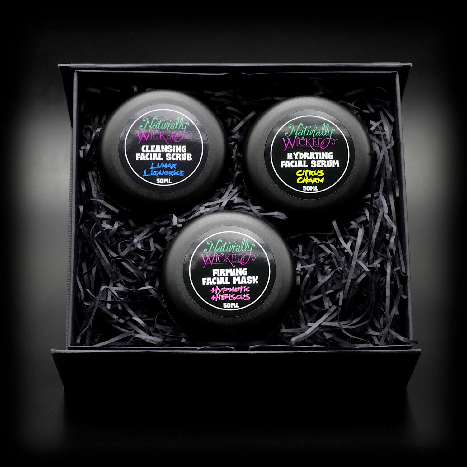 Elegant box with Naturally Wicked Cleansing Scrub, Hydrating Serum, and Firming Mask, each in sleek black 50ml tubs