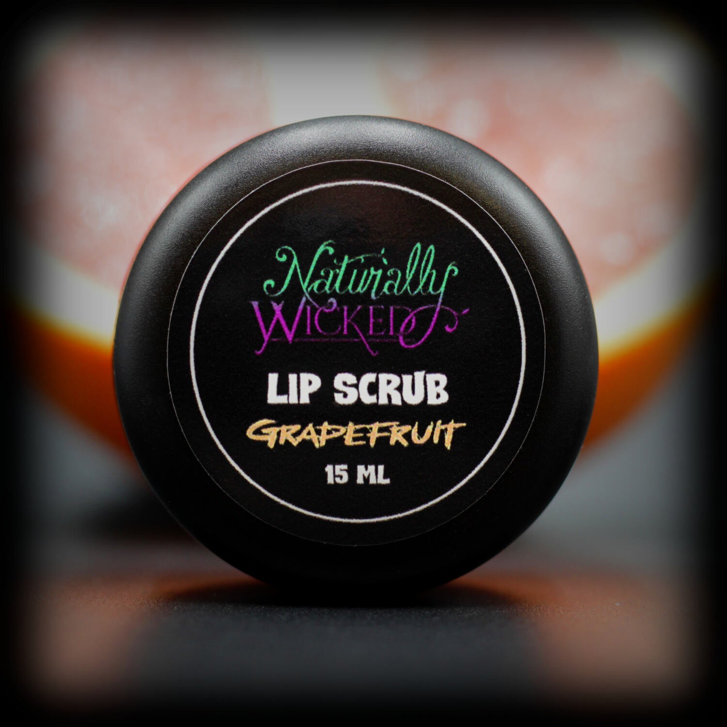 Naturally Wicked Grapefruit Lip Scrub Luxury Labelled Lid Beside a Juicy Sliced Grapefruit