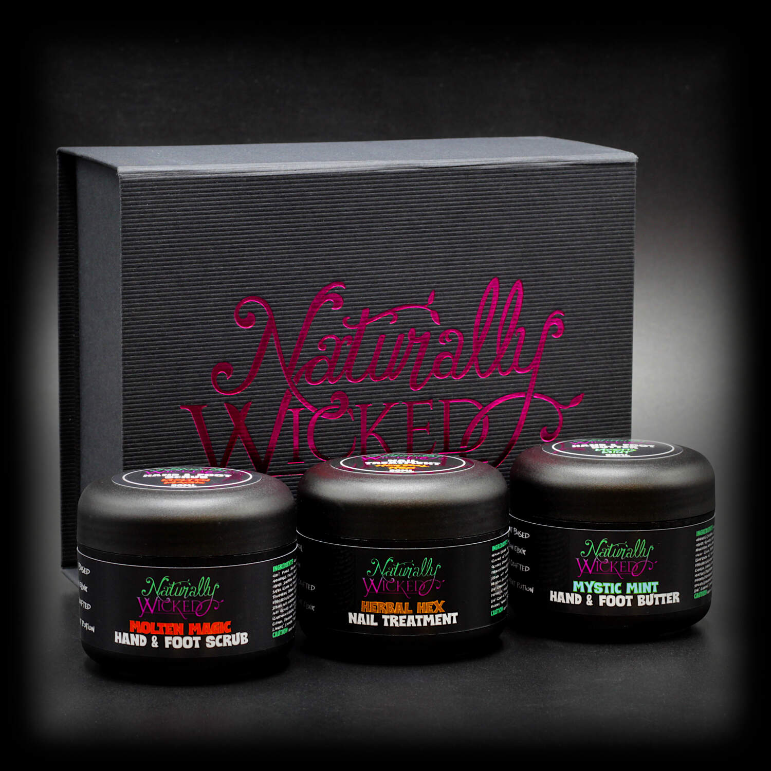 Naturally Wicked Original 3 Step Hand & Foot Kit With Molten Magic Hand & Foot Scrub, Herbal Hex Nail Treatment & Mystic Mint Hand & Foot Butter In Front Of Original Black & Pink Box