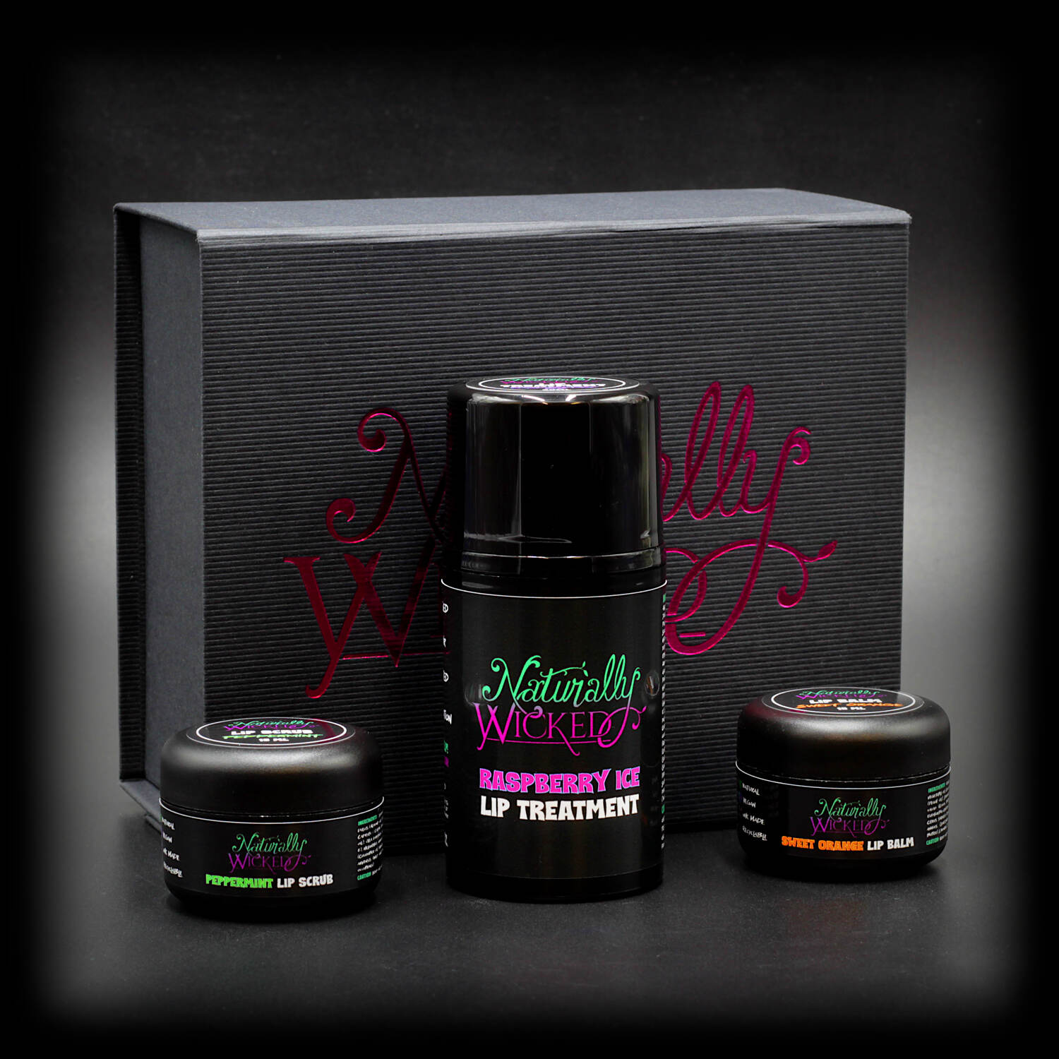 Naturally Wicked Lip Care Gift Set featuring Raspberry Ice Lip Treatment, Peppermint Lip Scrub, and Sweet Orange Lip Balm in a stylish black box.