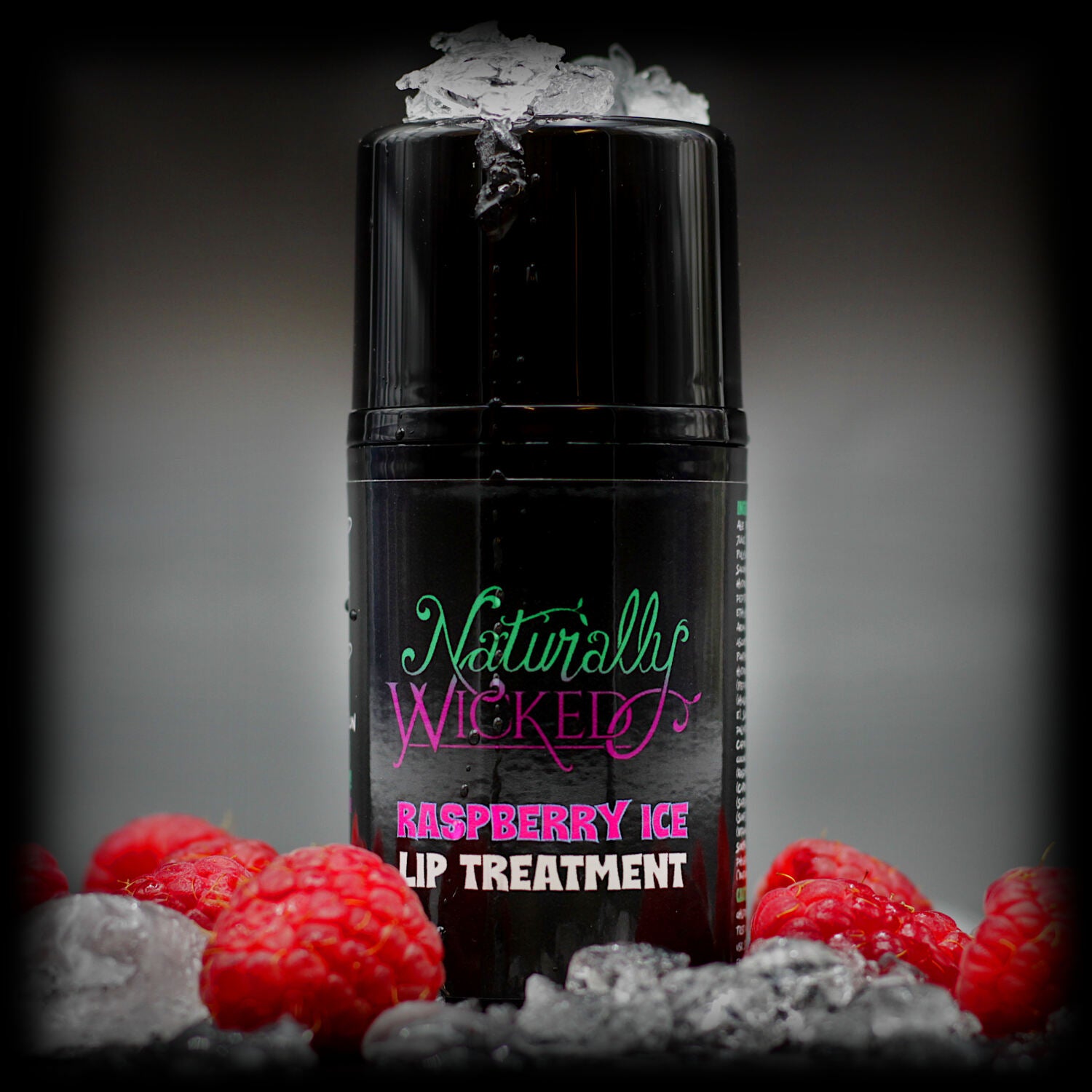 Naturally Wicked Raspberry Ice Lip Treatment Surrounded By Luscious, Red, Fruity Raspberries & Ice