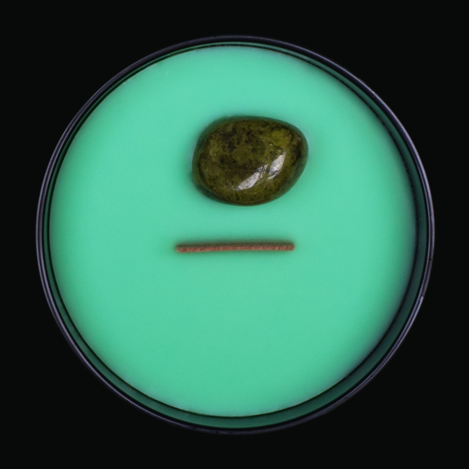 Naturally Wicked Spellbinding Luck Crystal Candle View From Above Shows Green Smooth Plant-based Wax, Featuring A Wooden Wick And Spotted Epidote Spell Crystal. All Situated Within A Black Gloss Glass Container. The Perfect Gift For That Lucky Person In Your Life