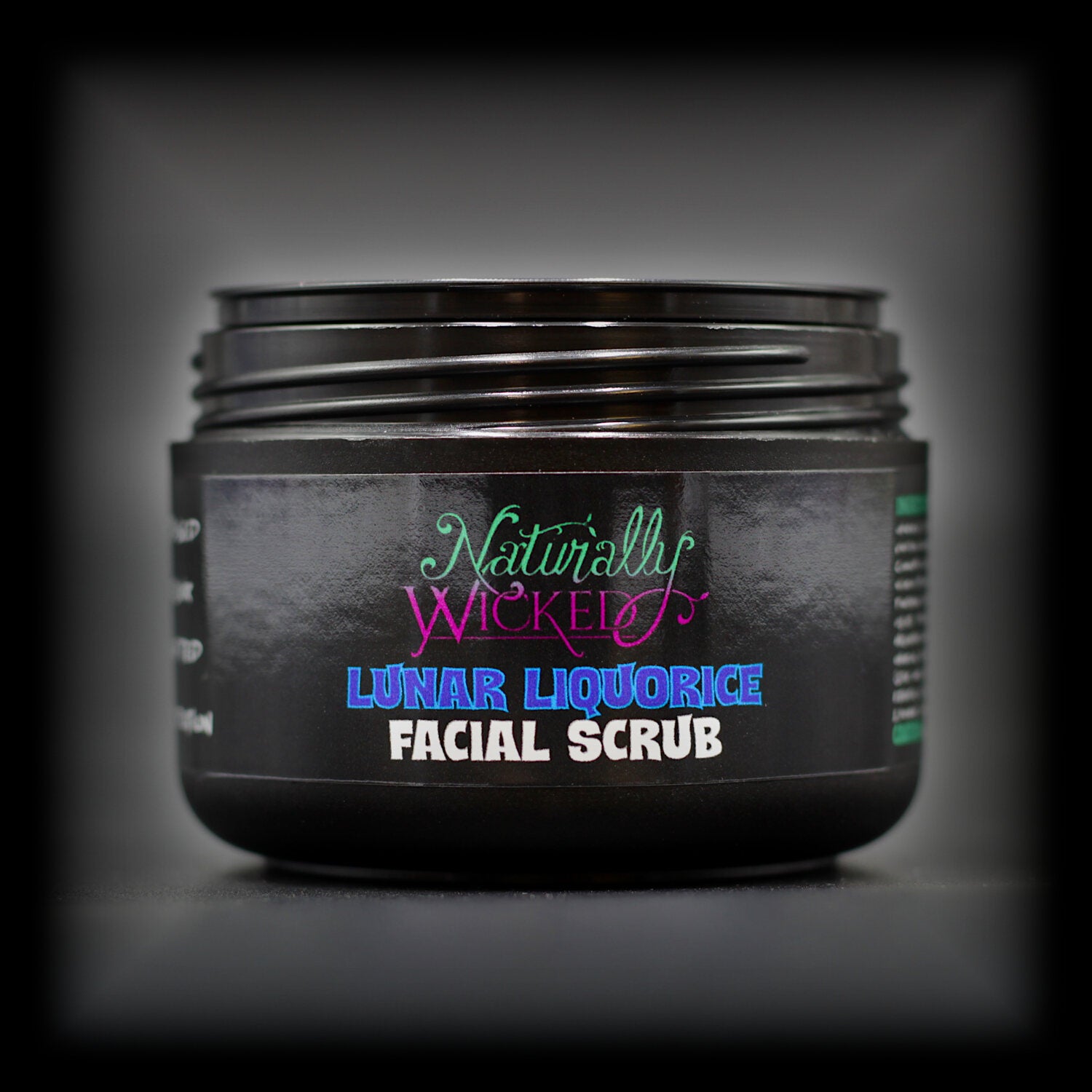 Naturally Wicked Lunar Liquorice Facial Scrub in black tub with lid off, showing bold blue and purple label.