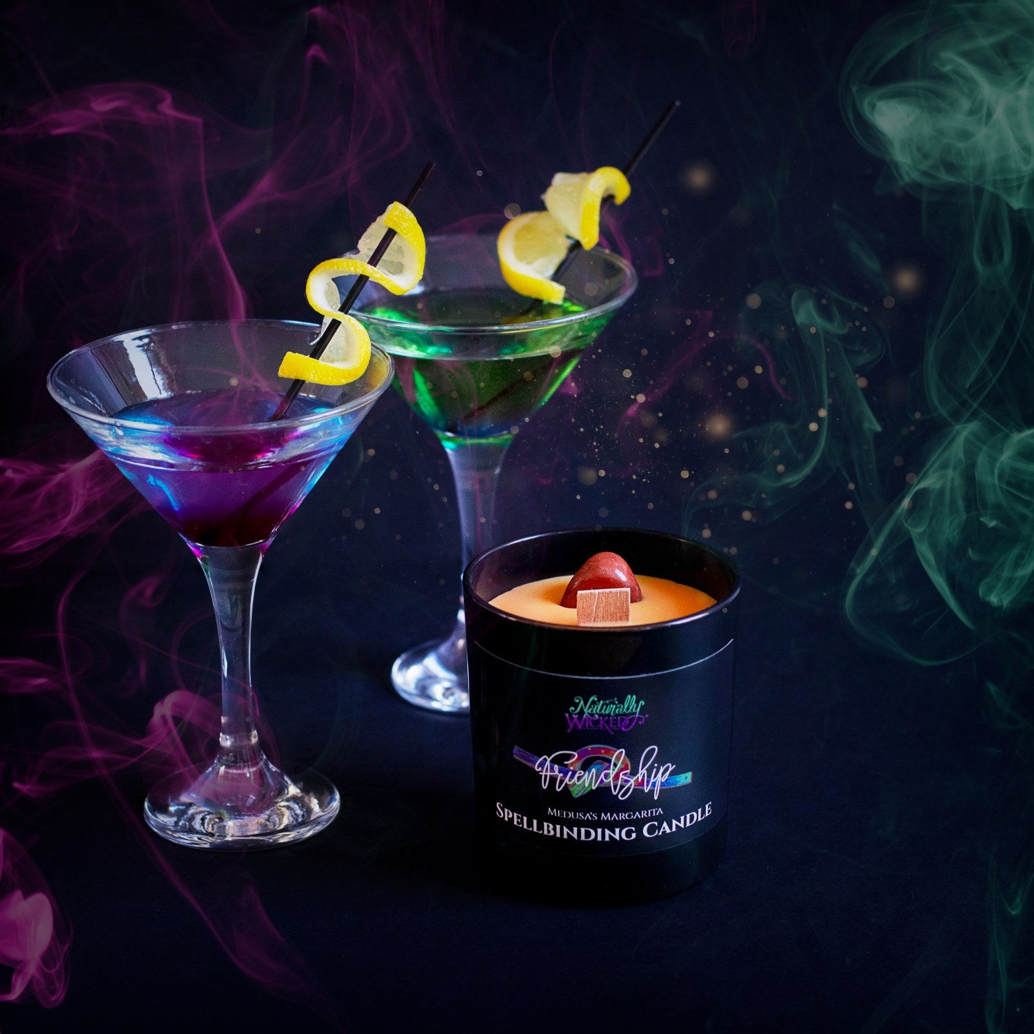 Naturally Wicked Spellbinding Friendship Spell Candle Entombed With Bright Orange Friendship Crystal Sits In Front Of Green & Purple Cocktails
