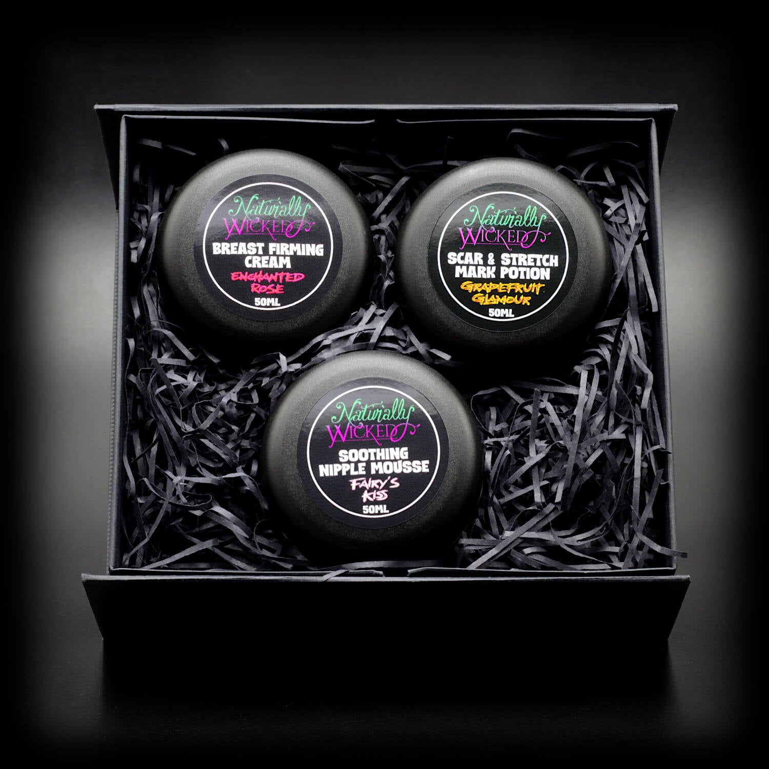 Black gift box containing Naturally Wicked’s Enchanted Rose Breast Firming Cream, Soothing Nipple Mousse, and Scar & Stretch Mark Potion