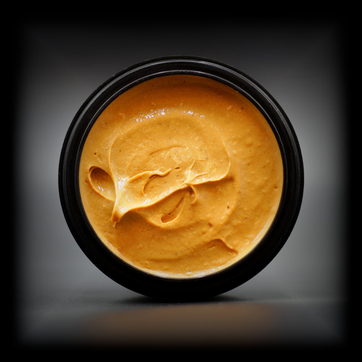 Top view of Naturally Wicked Molten Magic Hand & Foot Scrub with smooth, molten-orange texture in an open tub.