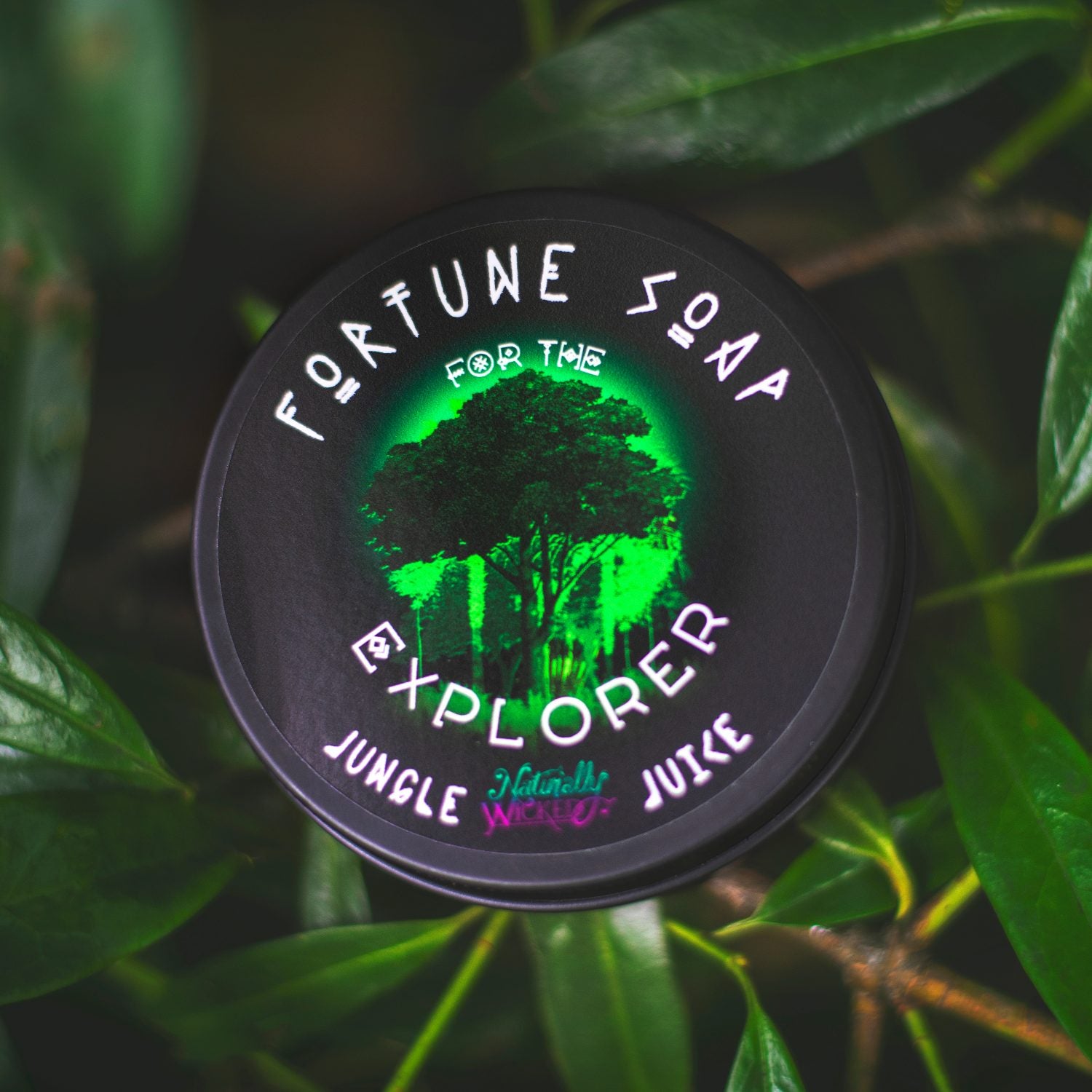 Naturally Wicked Fortune Soap For The Explorer In Jungle Juice container with green glow on a leafy background