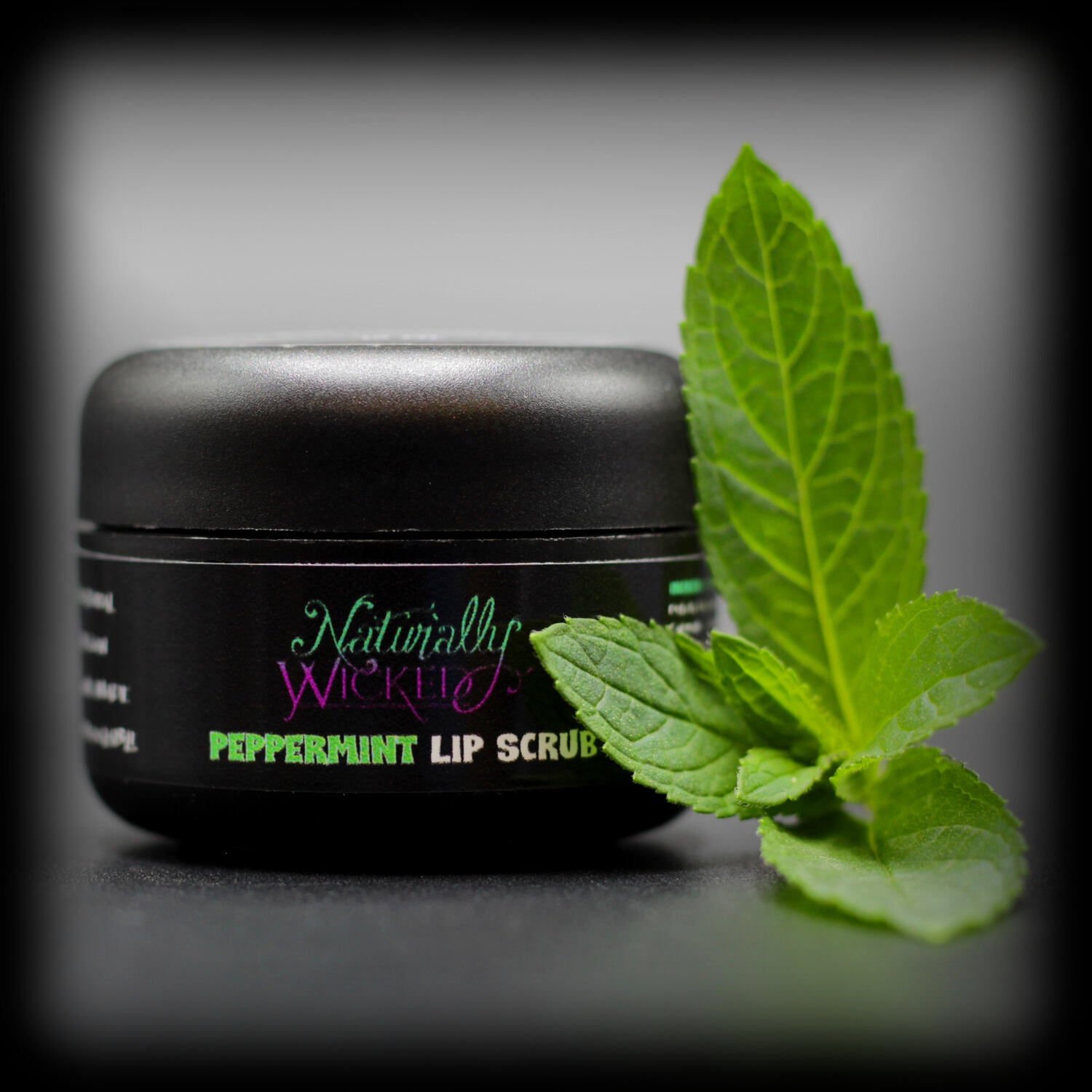 Naturally Wicked Peppermint Sugar Lip Scrub Surrounded By Refreshing Green Peppermint Leaves