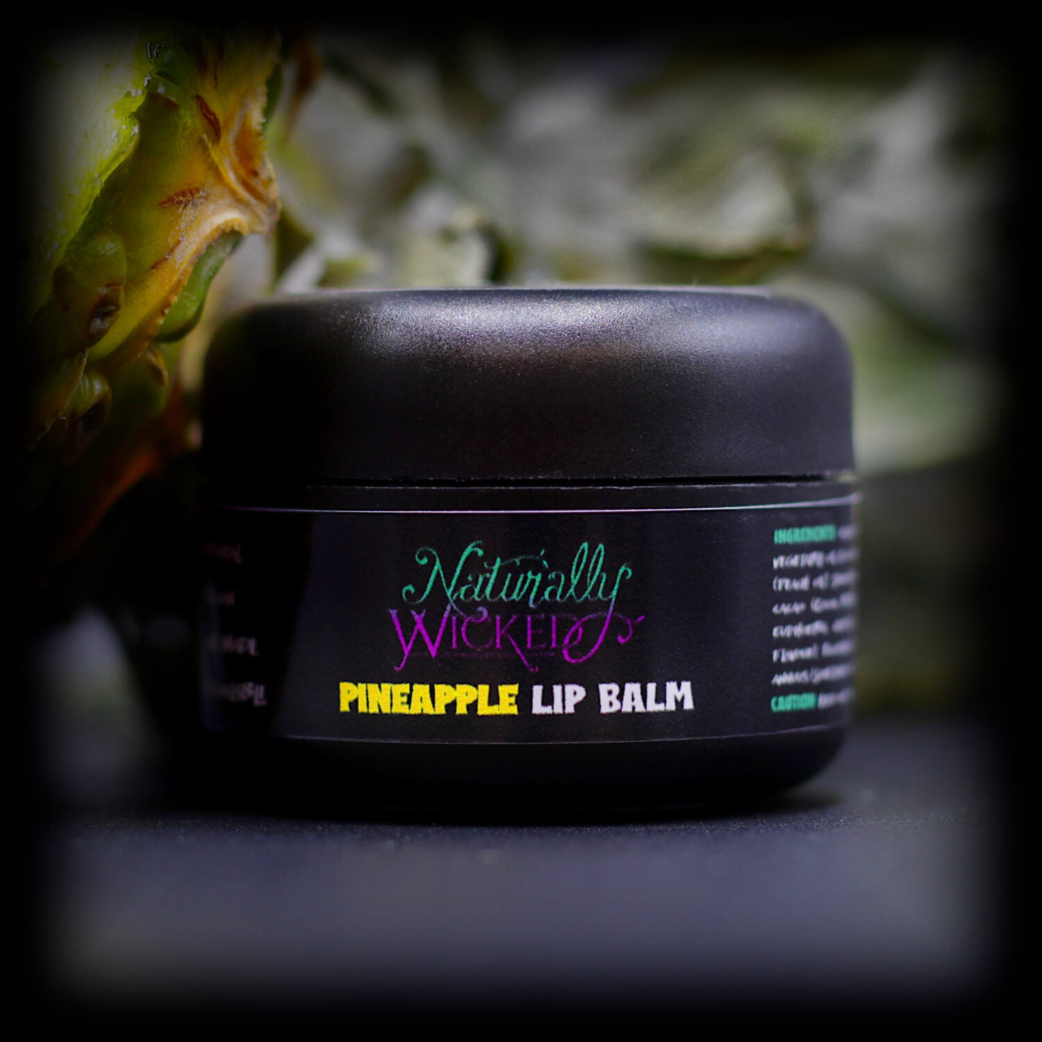 Naturally Wicked Pineapple Lip Balm Beside Fresh Green & Yellow Pineapple