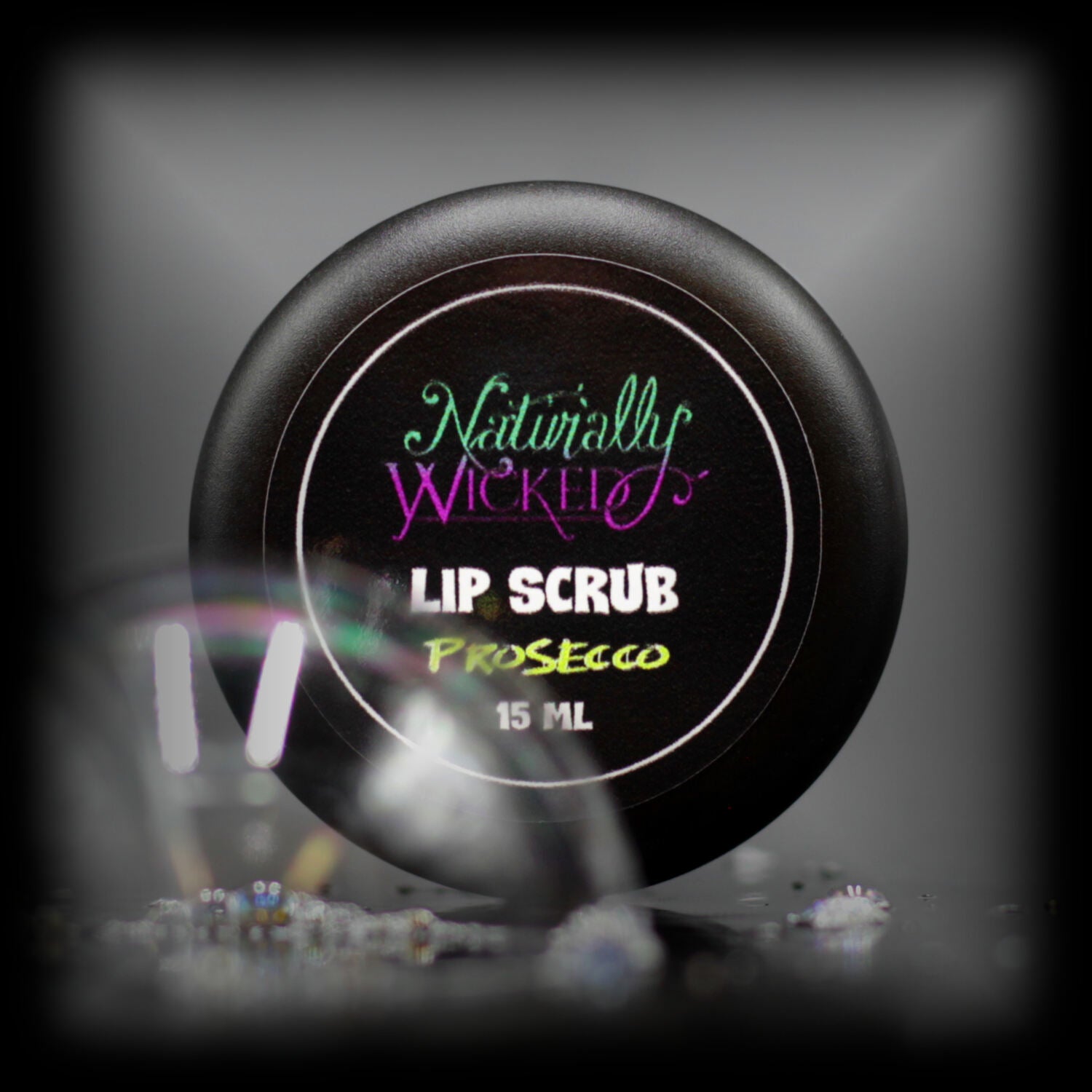 Naturally Wicked Prosecco Lip Scrub Luxury Labelled Lid Beside Shining Clear Bubble